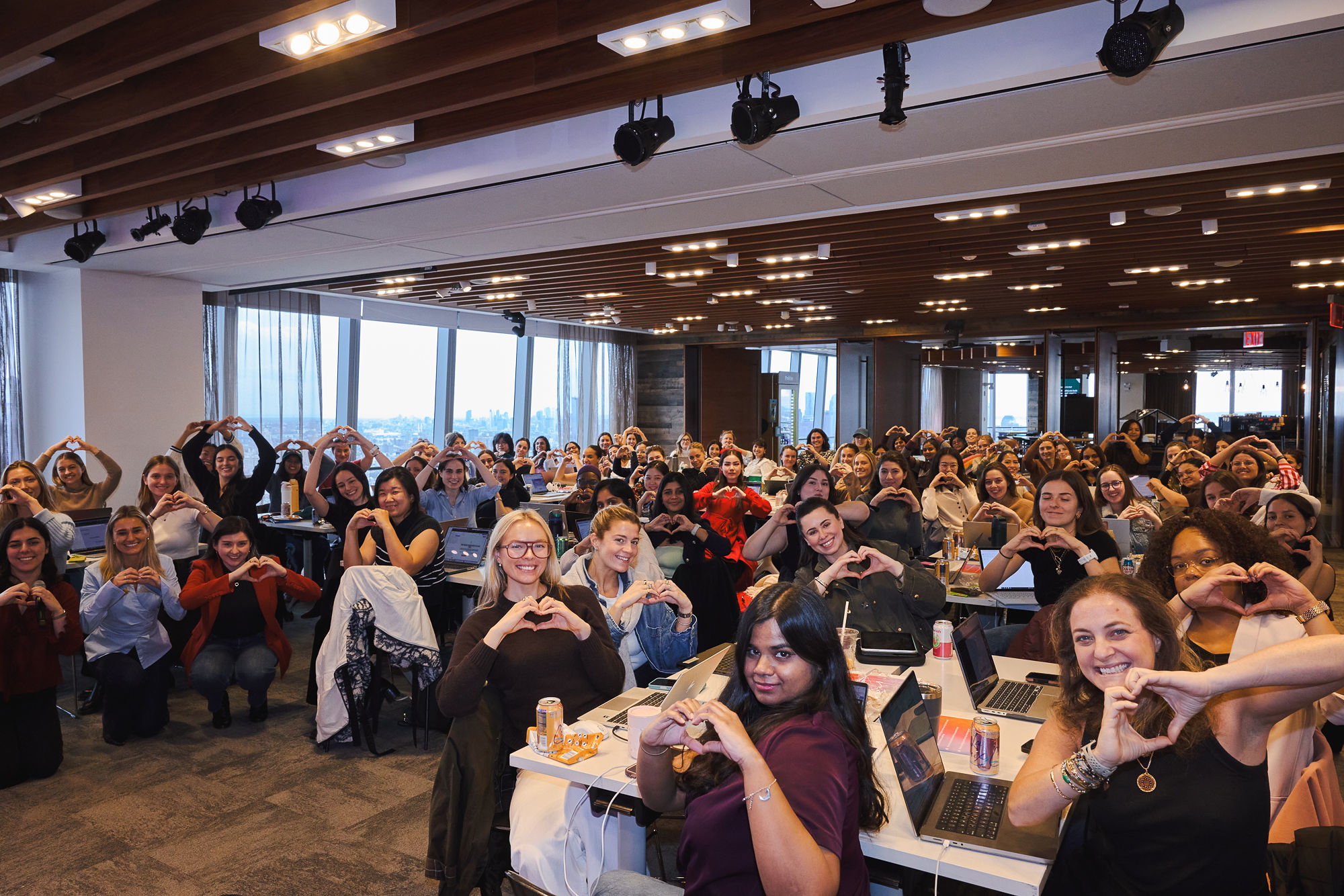 A full room of women making heart shapes with their hands at a Model Behavior event